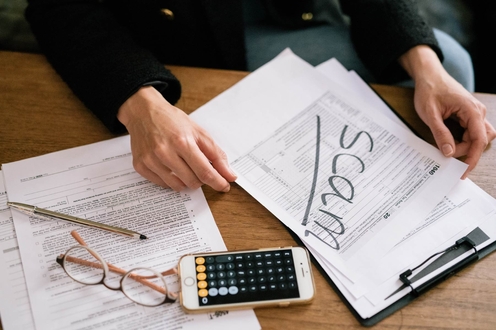 A person reviews financial documents at a wooden table,